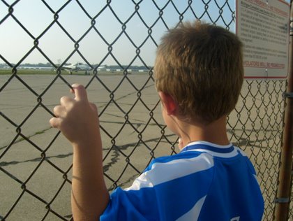 Boy Looking Through Airport Fence
